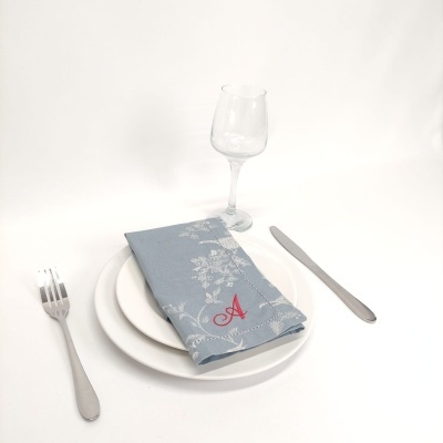 Conjunto de jantar com prato branco, talheres e guardanapo azul com letra A