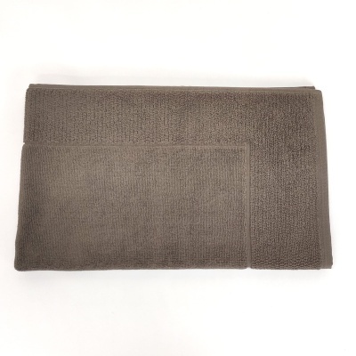 Toalha de banho castanho claro dobrada sobre fundo branco