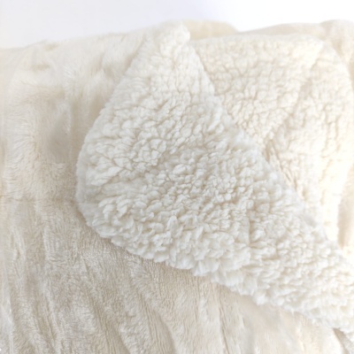 Manta bege claro com textura peluda de ovelha e superfície lisa aveludada.