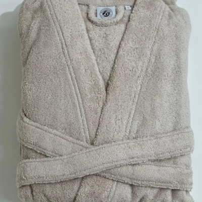 Robe de banho bege dobrado em tecido felpudo com cinto