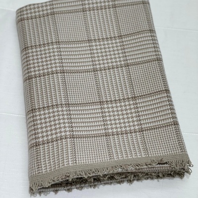 Pano tecido bege e castanho com padrão quadriculado e franjas