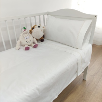 Cama branca de criança com roupa de cama branca e dois peluches sentados