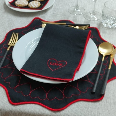 Conjunto de mesa com guardanapo preto bordado e talheres dourados sobre prato branco