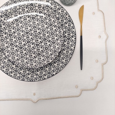 Conjunto de pratos de cerâmica com padrão floral azul escuro e faca dourada com cabo preto sobre base branca decorativa