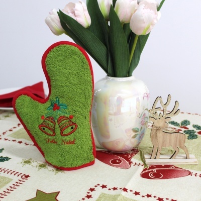 Manopla verde com sinos e 'Feliz Natal', vaso com flores e figura de alce em mesa decorada para Natal