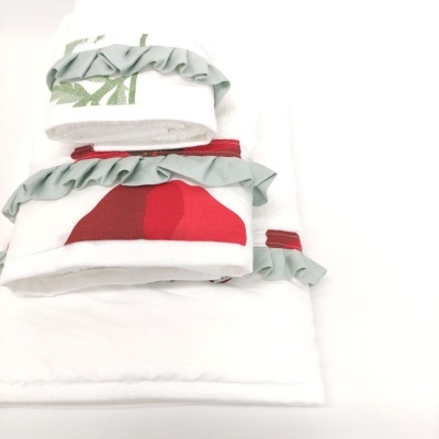 Toalhas brancas com detalhes azuis claros e estampas vermelhas e verdes com babados