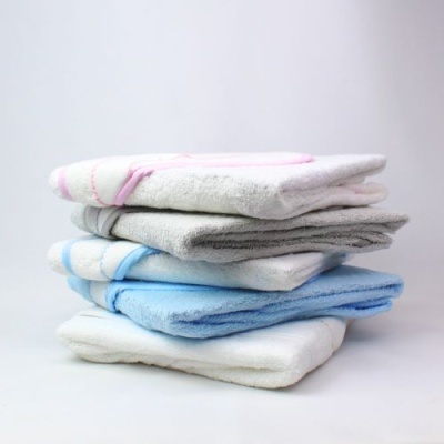 Toalhas de banho empilhadas em branco, azul clara, cinza e branco com detalhes rosa