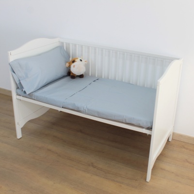 Berço branco com colchão e almofada cinza claro e pelúcia de vaca