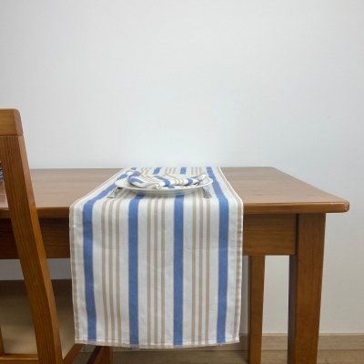 Mesa de madeira com toalha comprida listrada azul/bege/branco e prato branco
