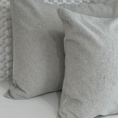 Duas almofadas cinzentas com textura suave e fundo branco com tecido tricotado