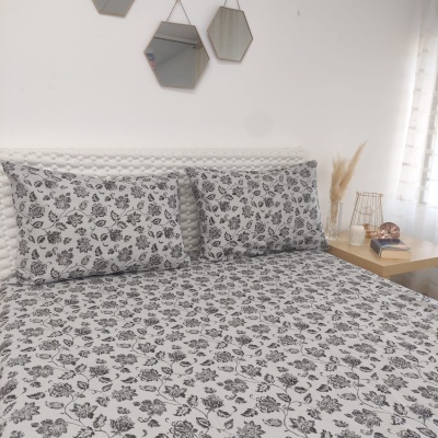 Conjunto de roupa de cama com padrão floral em preto e branco numa cama com almofadas e lençóis.