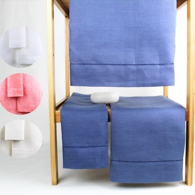 Toalhas de banho em azul, branco e rosa penduradas numa estrutura de madeira