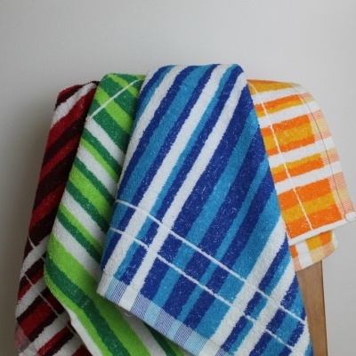 Quatro toalhas coloridas com riscas penduradas num cabide de madeira
