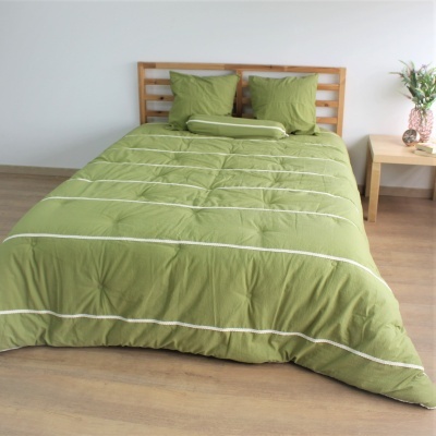 Cama com edredão verde e almofadas, madeira e mesa de cabeceira