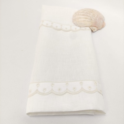Guardanapo branco com bordado em linha creme e concha ao lado