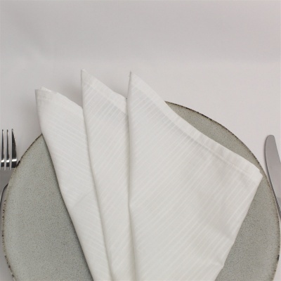 Guardanapos brancos sobre prato cinza com talheres ao lado