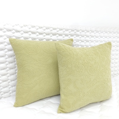 Almofadas verdes claras com padrão texturizado em sofá branco acolchoado