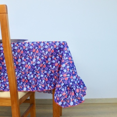 Toalha de mesa floral com borda franzida numa mesa de madeira