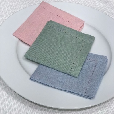 Três guardanapos de tecido em tons pastel sobre prato branco