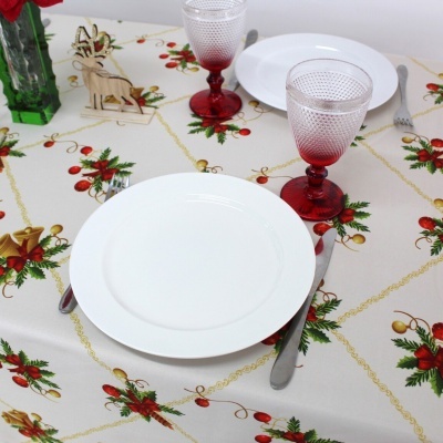 Mesa posta com toalha natalícia, prato branco, talheres, taça vermelha e decoração de rena em madeira