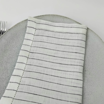 Guardanapo branco riscado sobre prato cinzento com garfo