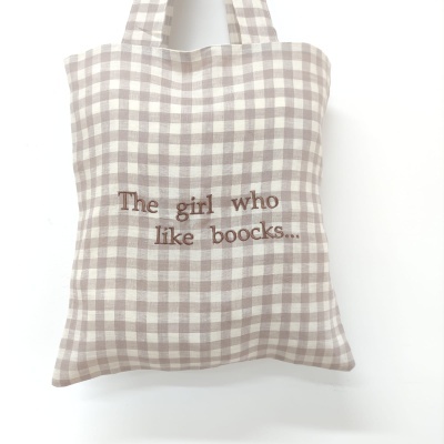 Mala xadrez bege e branco com texto bordado 'The girl who like boocks...'