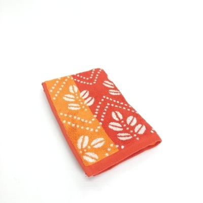 Toalha dobrada com padrão de folhas em laranja e vermelho