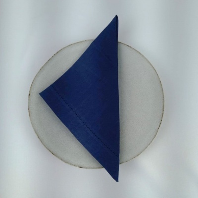 Guardanapo azul sobre prato branco com borda dourada