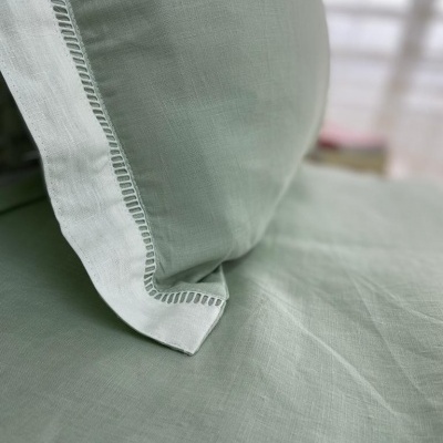 Travesseiro e lençol verde claro em linho com costura decorativa aberta nas bordas do travesseiro