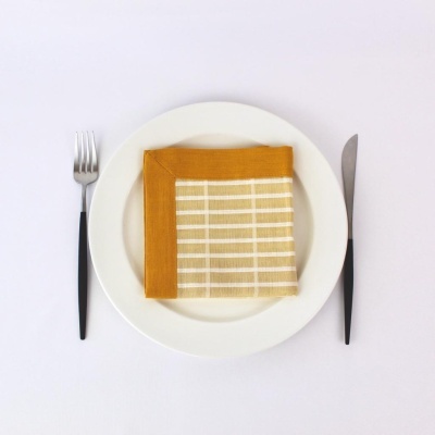 Prato branco com guardanapo listrado bege e castanho, garfo e faca com cabos pretos