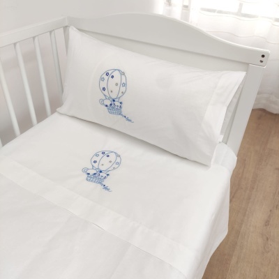 Jogo de lençóis branco para berço com bordado azul de balão em berço branco