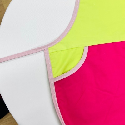 Têxteis coloridos com bordas rosa sobre mesa branca e preta