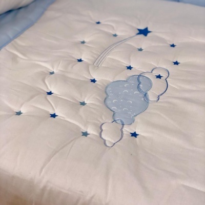 Colchão ou almofada branca com bordado azul de nuvem e estrelas