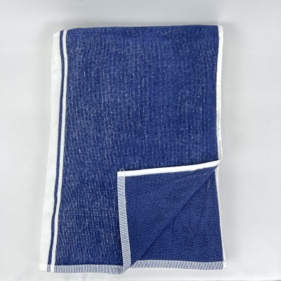 Toalha azul com borda branca e risca dupla azul escura, parcialmente dobrada
