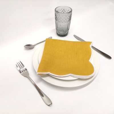 Prato branco com guardanapo amarelo e talheres em fundo branco