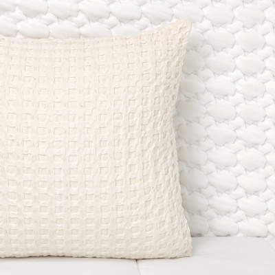Almofada branca texturizada sobre sofá branco trançado