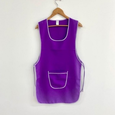 Avental roxo com contornos brancos pendurado num cabide de madeira