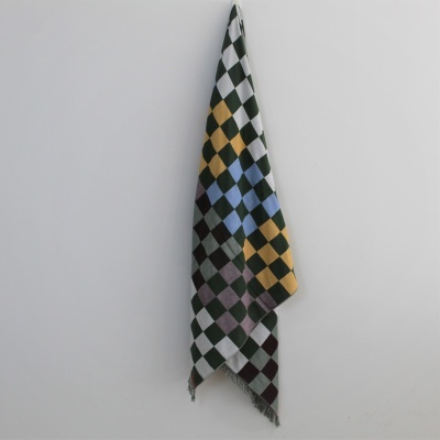 Toalha ou manta xadrez colorida pendurada numa parede clara