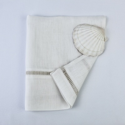 Toalha branca com bordado e concha marinha em fundo branco