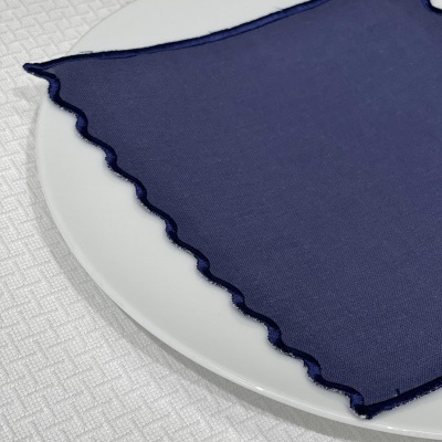 Guardanapo azul escuro com borda ondulada sobre prato branco