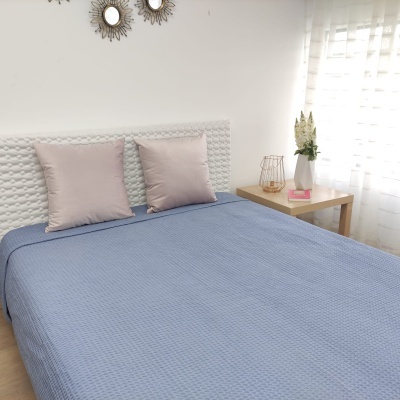 Cama com colcha azul e almofadas cor de rosa numa decoração de quarto minimalista