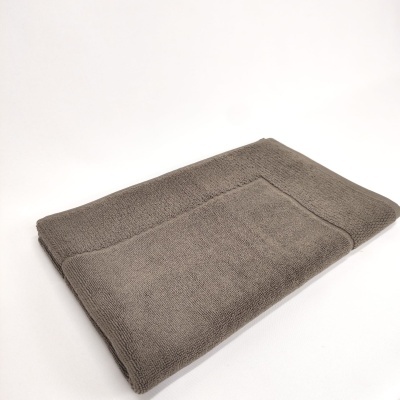 Toalha de banho cinzenta dobrada numa superfície branca