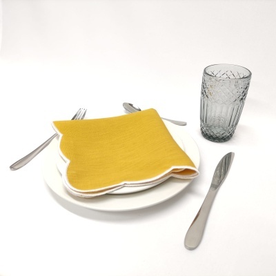 conjunto de mesa com prato branco, guardanapo amarelo, talheres de metal e copo de vidro