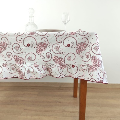 Toalha de mesa branca com padrão vermelho decorativa sobre mesa de madeira com decantador e taça de vidro