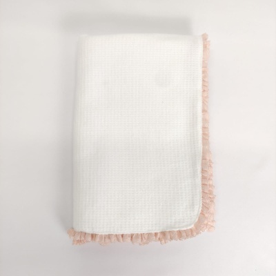 Toalha branca com franjas rosa dobrada sobre superfície branca