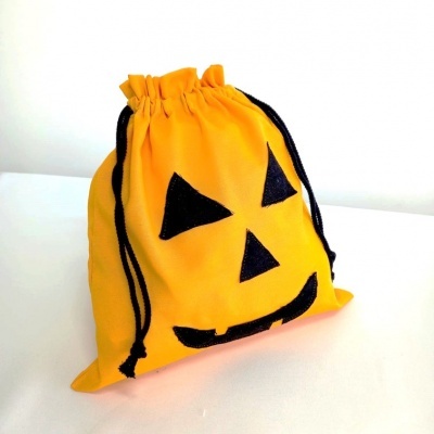 Saco amarelo com rosto de abóbora preto e cordões pretos