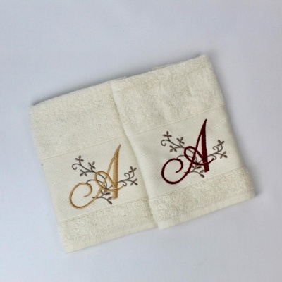 Duas toalhas bege claras com monogramas V e A bordados em cores diferentes