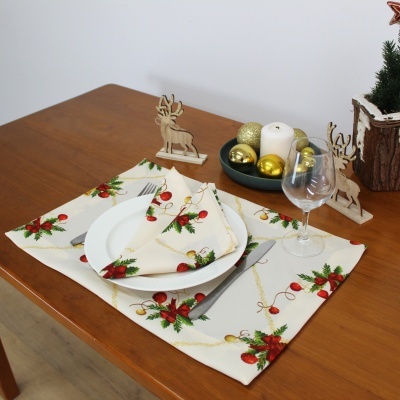 Mesa de Natal com jogo americano e guardanapo estampados, prato branco, talheres cinzentos, taça de vinho, vela e decoração natalícia com renas de madeira.