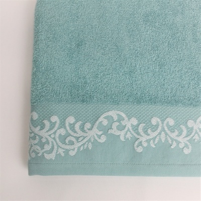 Toalha azul clara com bordado decorativo branco na barra