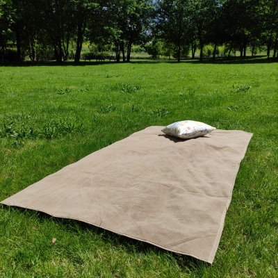 Tapete bege com almofada branca florida sobre relva verde num parque